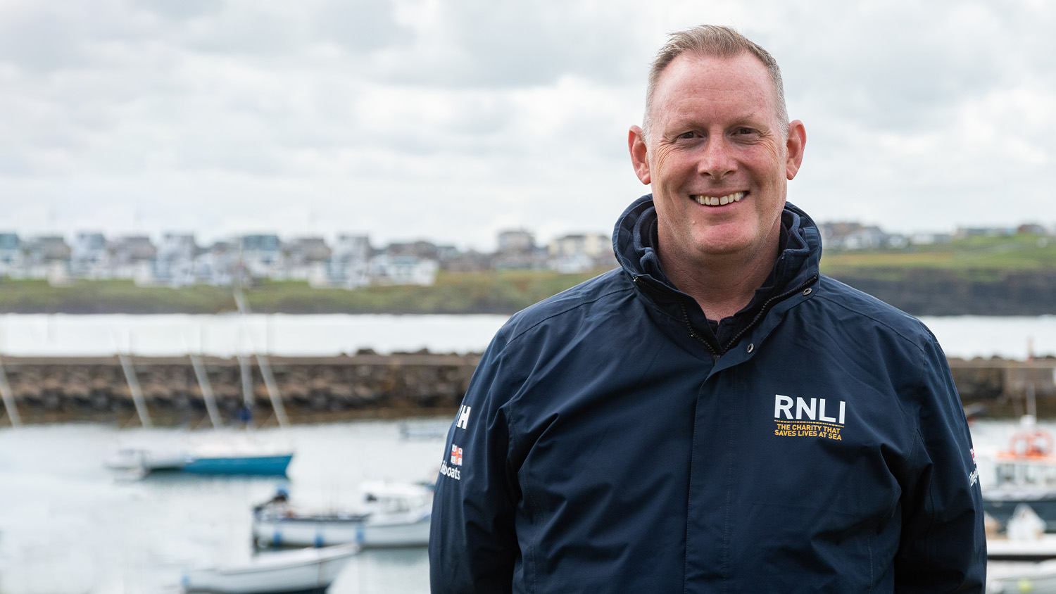 Face to face fundraiser wearing an RNLI jacket with the sea in the background