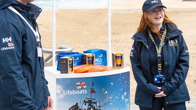 Face to face fundraisers raising money on a beach next to a stand