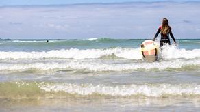 RNLI Lifeguard heading out to sea from the beach on a lifesaving board