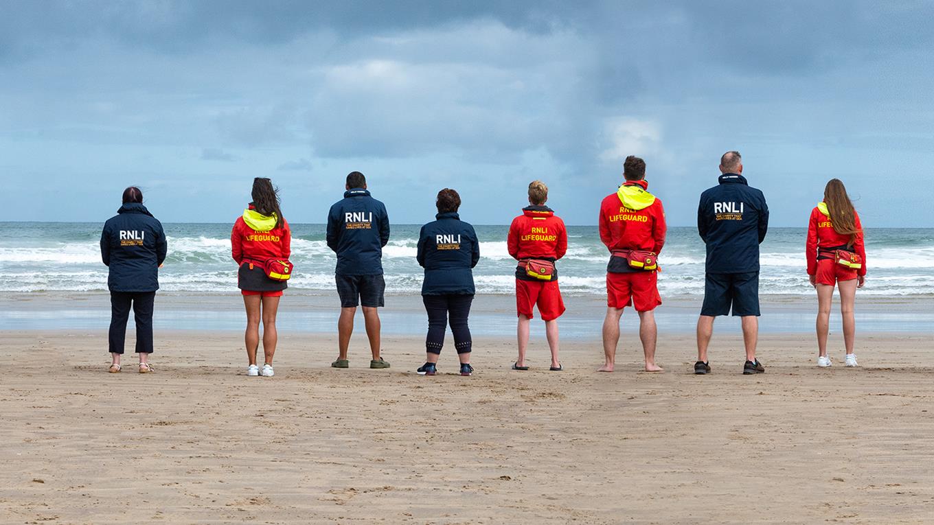 RNLI Lifeguards and face to face fundraisers standing together on a beach